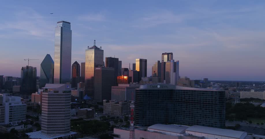 Downtown buildings and skyscrapers in a big city skyline as an airplane flies over town