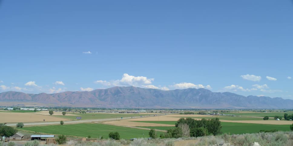 Cars travel down a road in the distance of this rural area