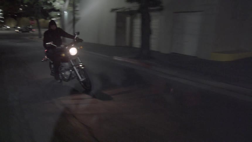 A man is riding a motorcycle turning back and forth in the street at night