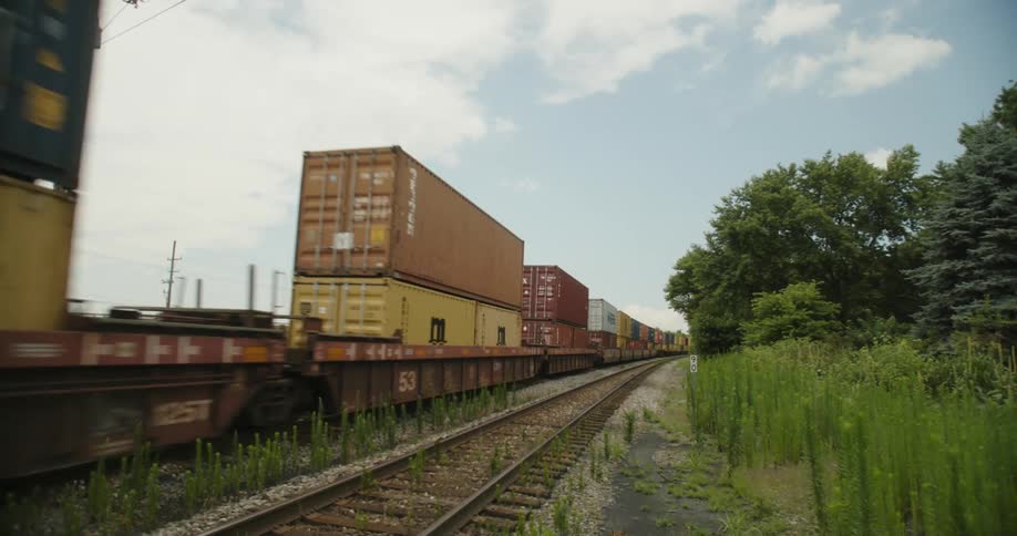 A train shipping cargo boxes drives down train tracks