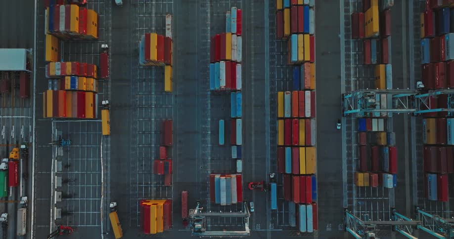 Large trucks turn down rows of cargo shipping containers