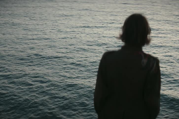 A person stands and looks out at the sea