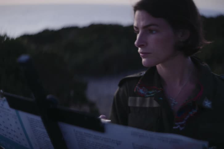 Female artists stands outdoors near hill painting