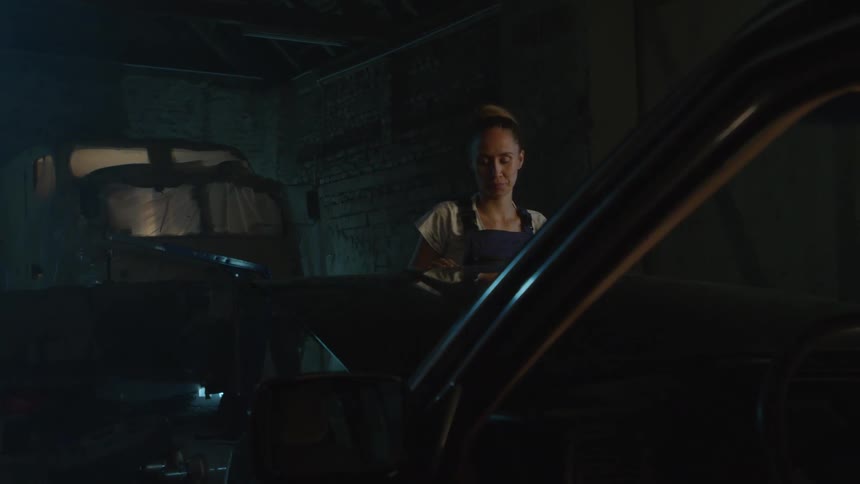 There is a young woman that is working on a car to fix it