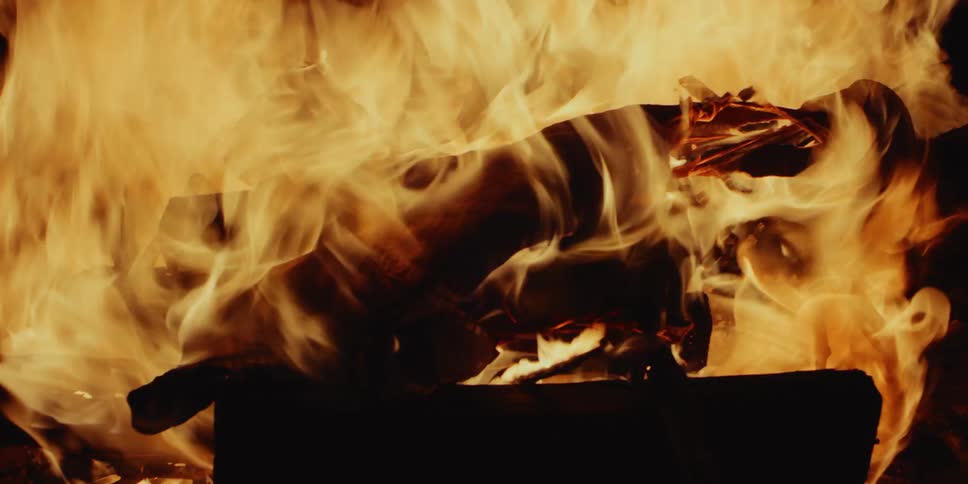 Tall flames billow from a bonfire