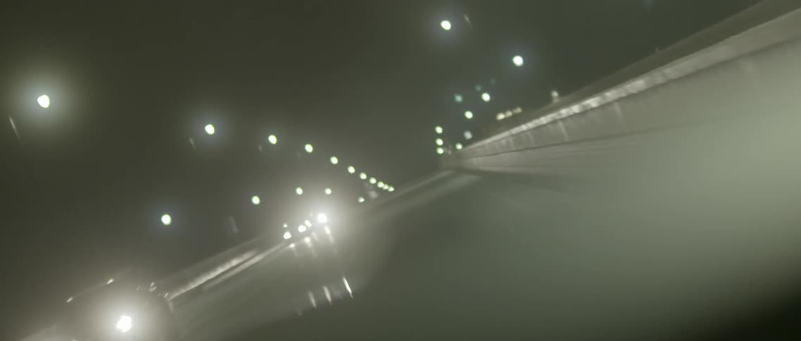 Seeing through the windshield of a car driving over a bridge at night