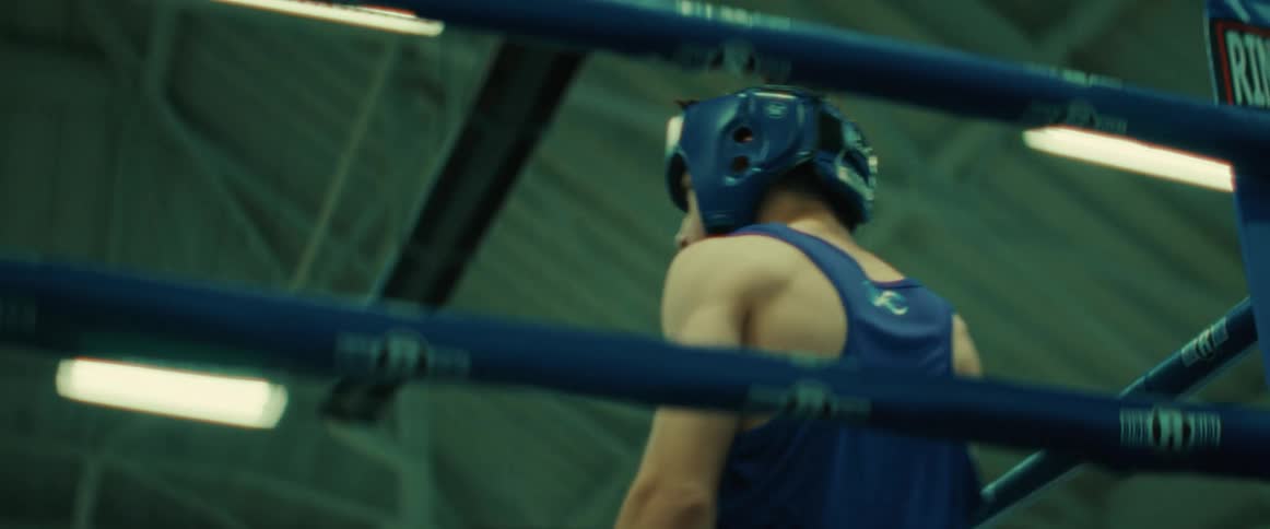 There is a young teenage boy that is inside of a boxing ring
