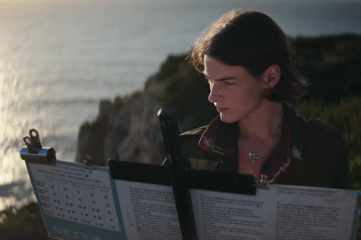 A woman is working on an easel by the shore
