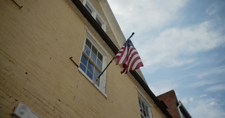 A flag flies from a pole attached to a window on a building