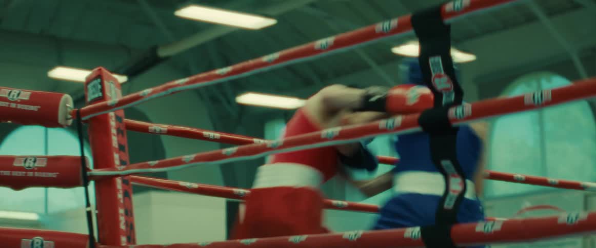 Two boxers wearing protective headgear sparring on a boxing ring