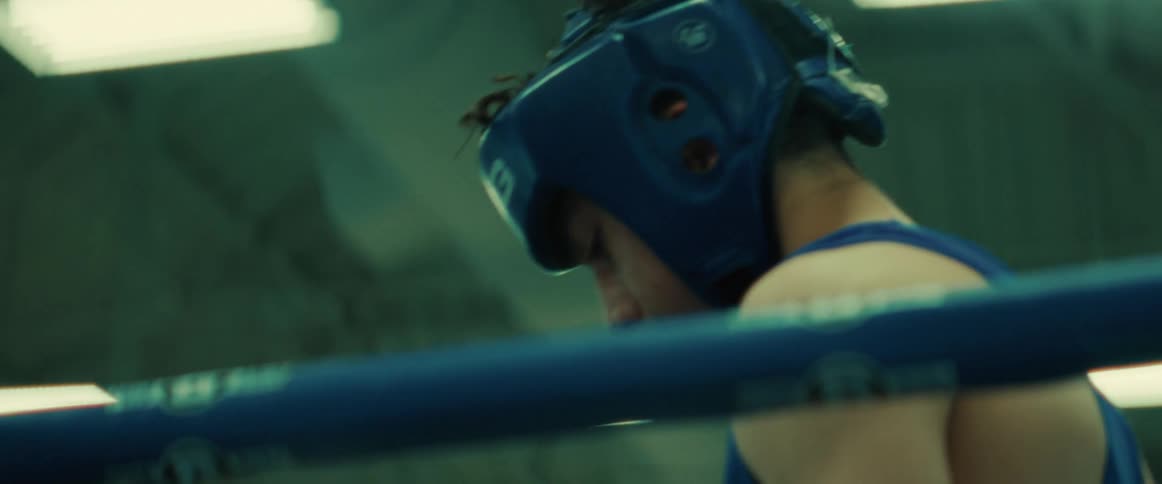 There is a young teenage man that is inside of a boxing ring