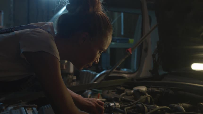 A female mechanic is fixing an engine