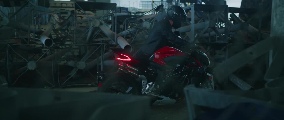 There is a young man riding on a motorcycle outside at night time