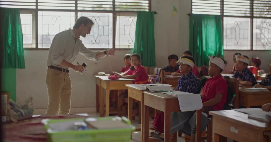 A teacher is teaching a class in front of all these kids