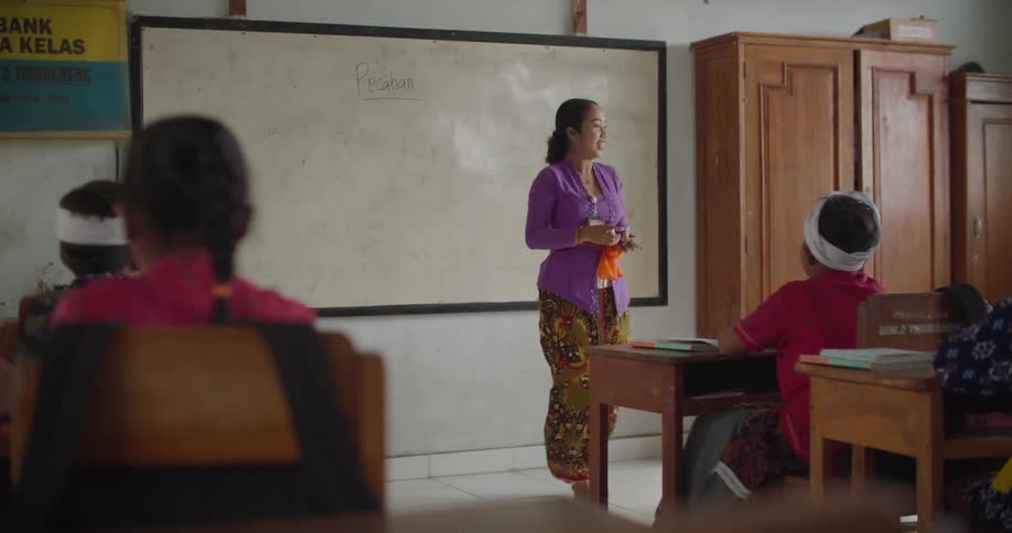 A teacher is teaching her students inside of the classroom