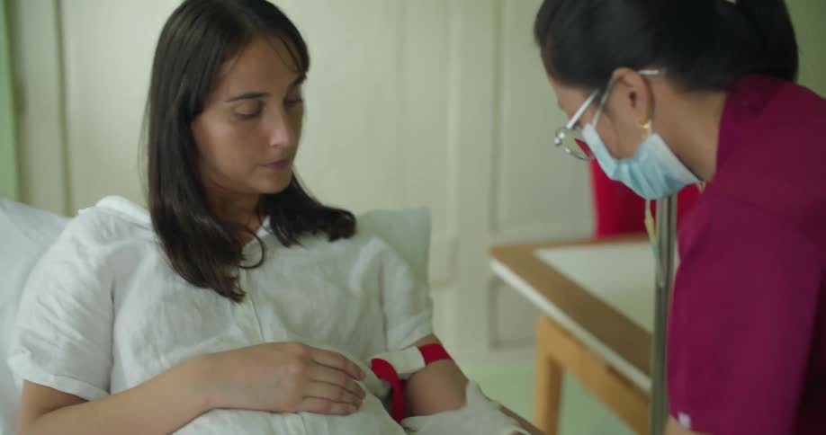 A young white woman is in a hospital and is getting treated by a nurse
