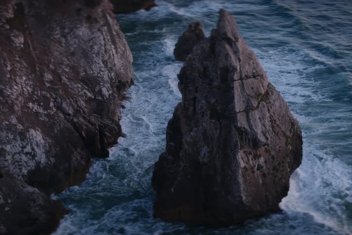 Waves splash as they roll into shore among rocks along the coast