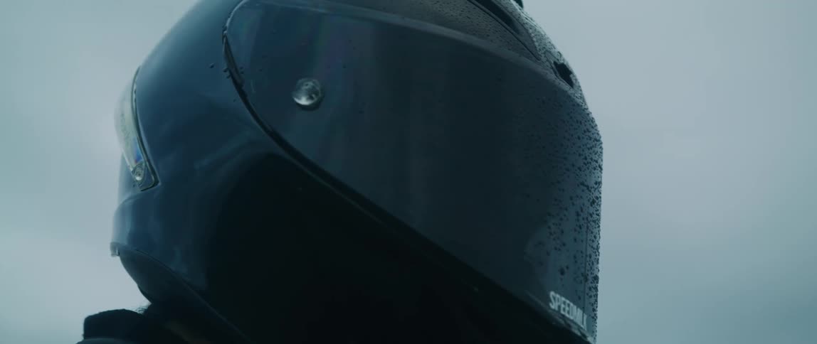 A person is wearing a motorcycle helmet in the rain