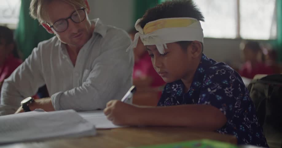 There is a teacher that is helping a student inside of a school