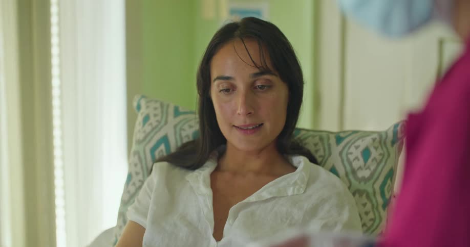 A young woman is laying down at the hospital talking to a nurse