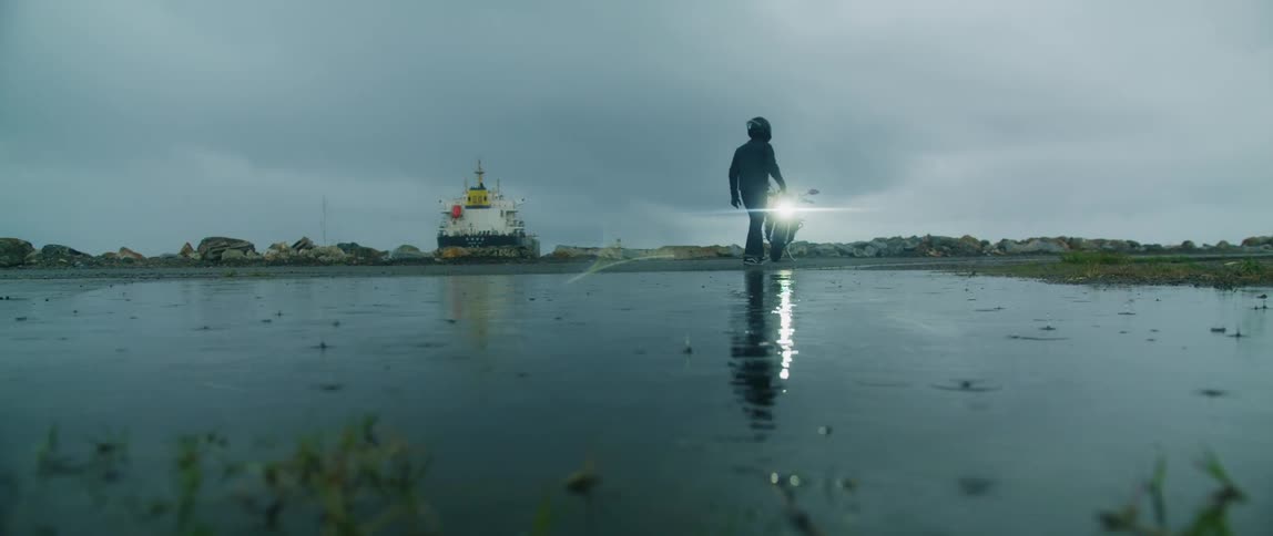 A young white man is walking to his bike in the middle of the lake