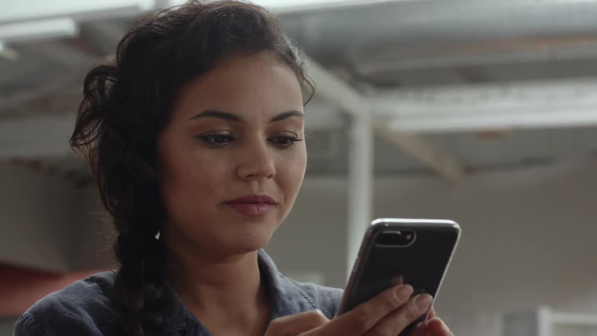 A woman is looking at her cell phone and smiling