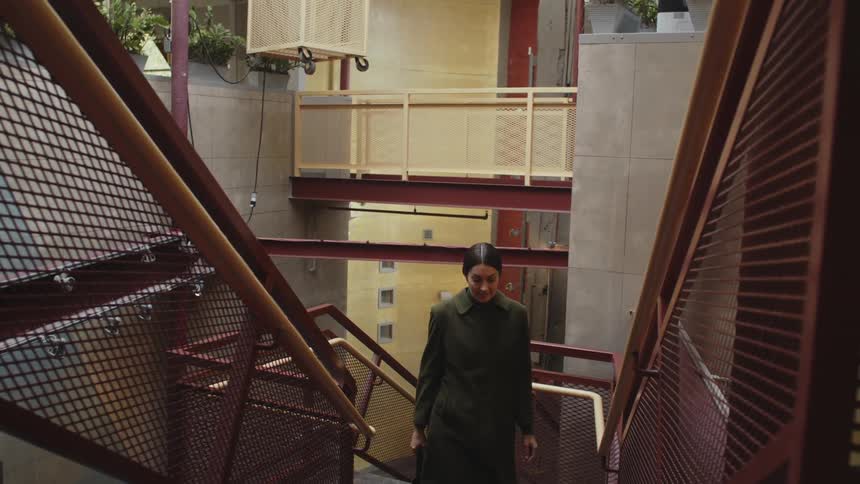 Woman looks up stairs enclosed in metal mesh staircase