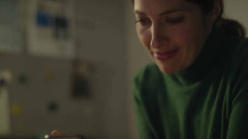 Woman wearing turtleneck smiles while viewing mobile phone