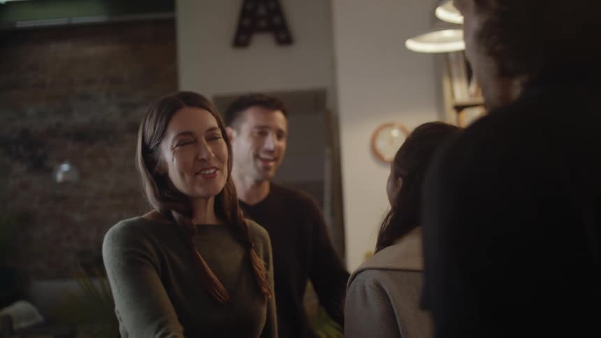 Group of friends greeting each other with hughs and handshakes at home
