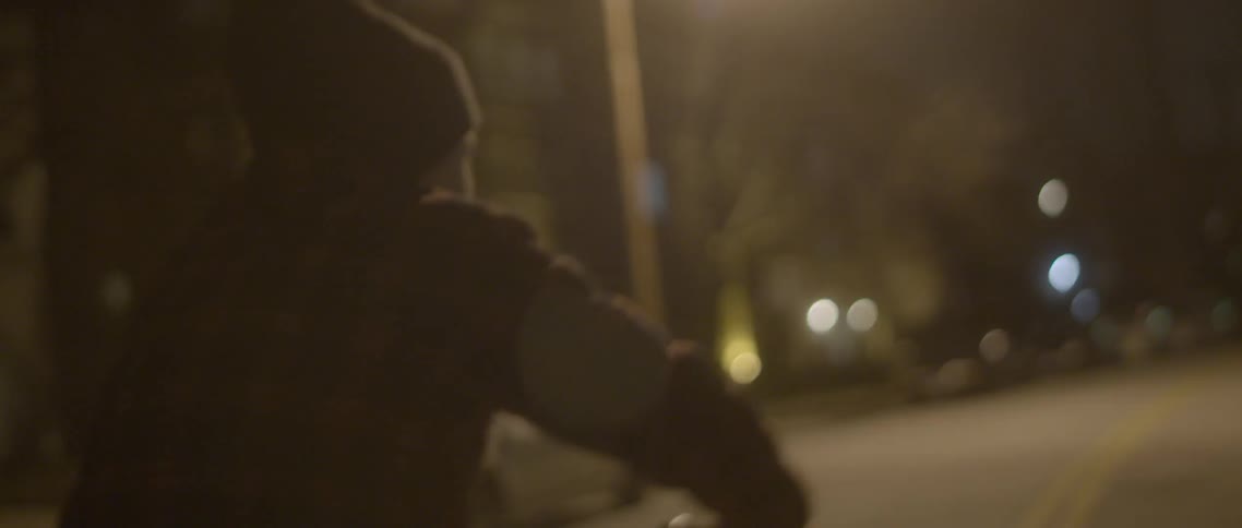 A boy rides his bike down a dark road