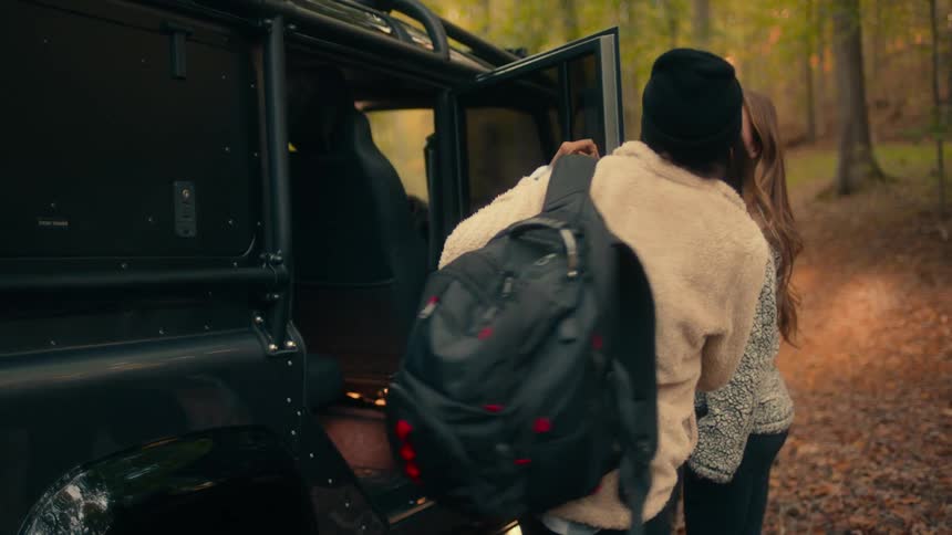 Two women exit the vehicle in the woods