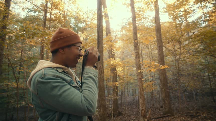Man takes pictures with a camera of a group of friends standing in the forest at morning