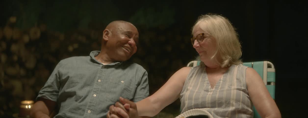 An older couple is holding hands and talking outside at night time