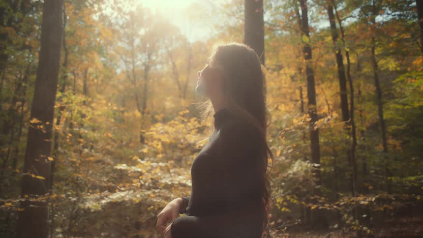A young white woman is walking outside in the nature area