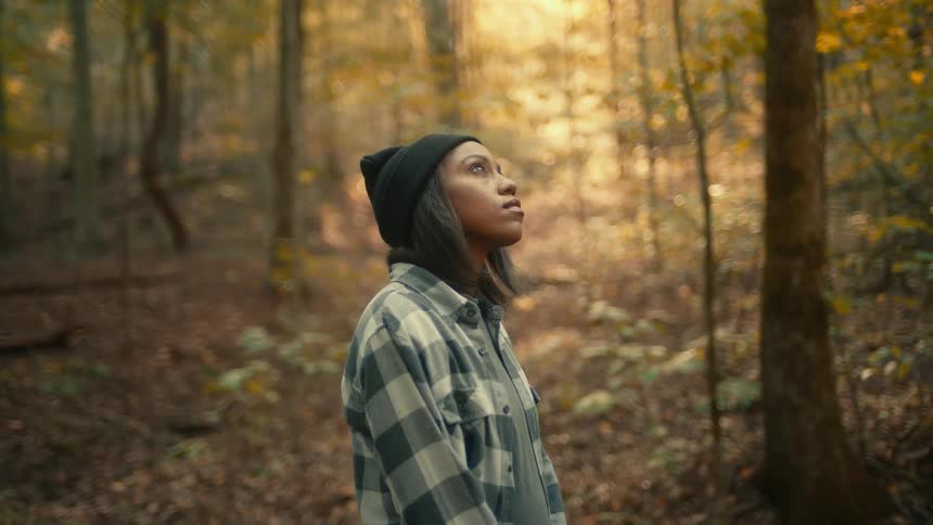 A young black woman is walking outside in the forest area