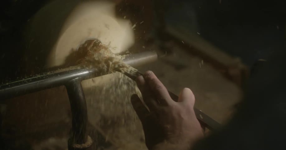 Man uses tool to bore hole in spinning wood