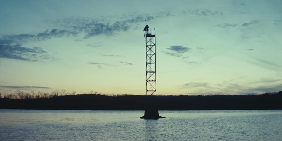 The tower of an oil rig stands above the water and reaches into the sky