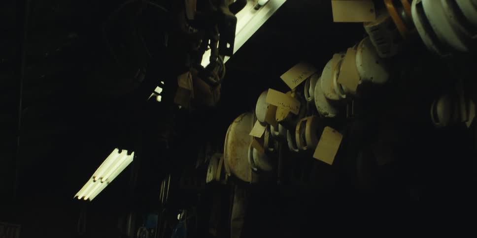Machine parts sit stacked on a tall shelf in a dark room