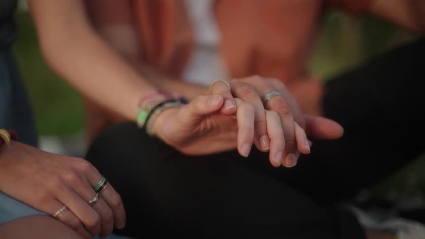 A couple hold hands while sitting in a park