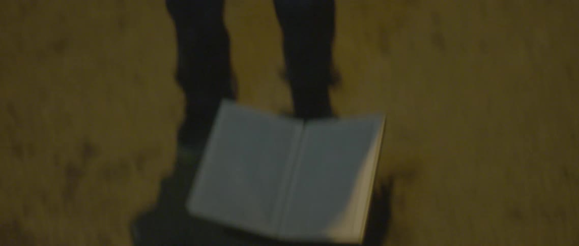 A boy holding a flashlight drops a book