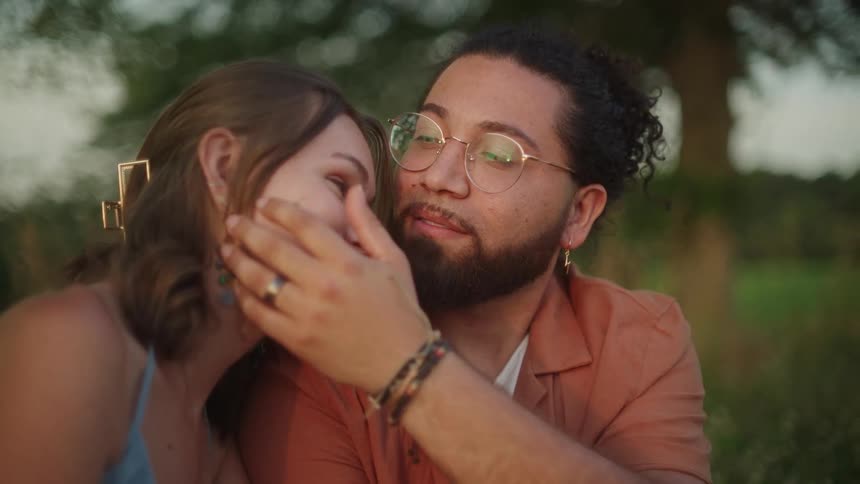 A woman is resting her head on a mans shoulder as he caresses her face