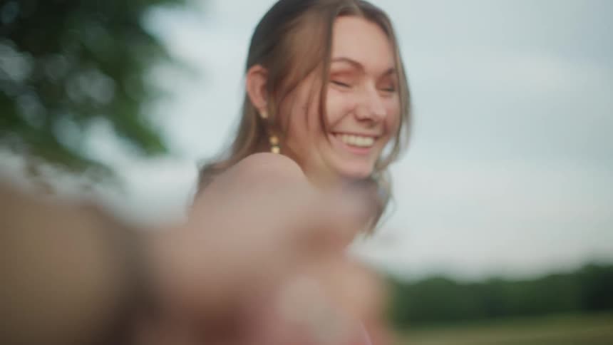 A woman laughs as she is walking forward and pulling a mans hand she is holding