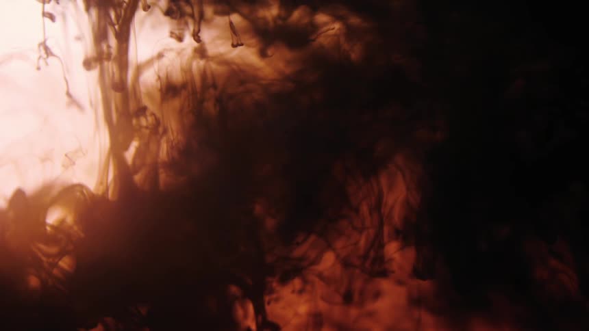 A body of liquid has dark swirls floating around and falling in