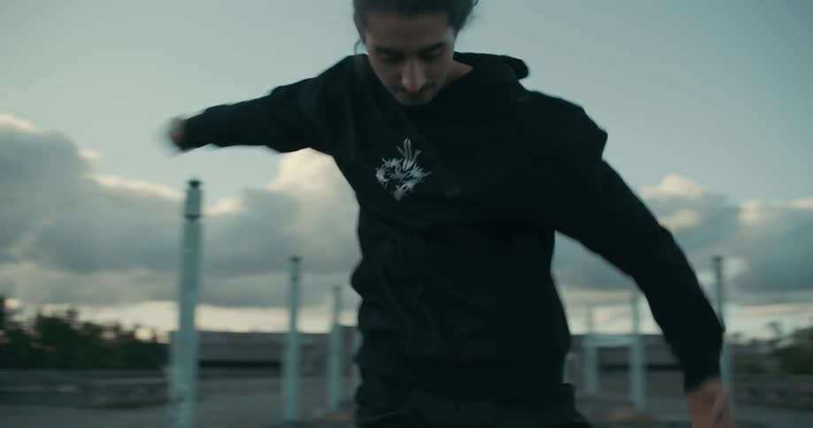 A man twirls and moves his arms up and down while dancing outside