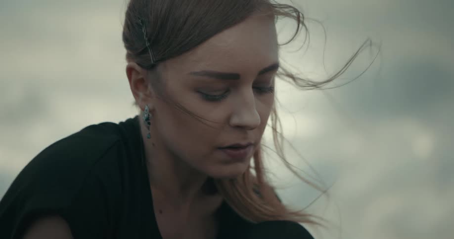 Wind blows through a womans long hair while she sits outside
