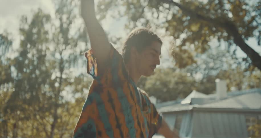 Young tattooed man trying to maintain balance on the backyard at morning