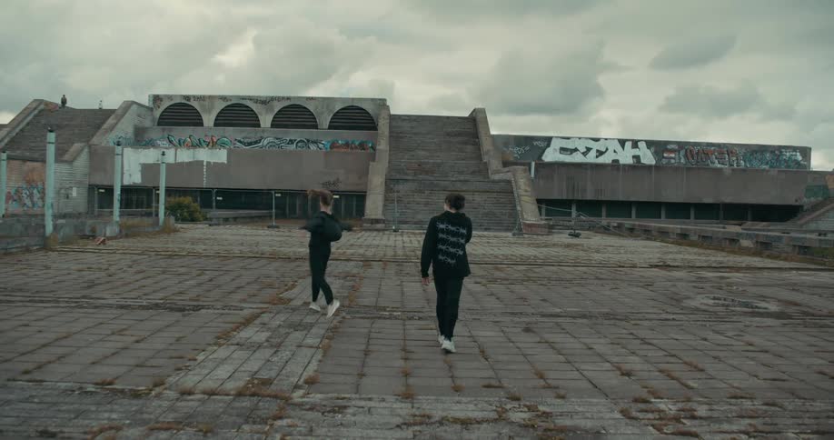 A woman twirls as she and a friend walk on the stone of the linnahall in estonia on a cloudy day