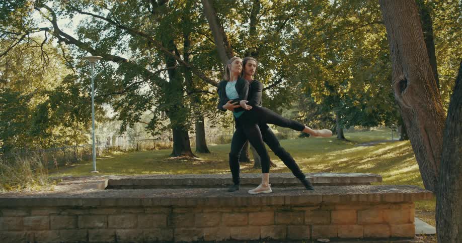 A man holds a womans arms and puts them around her waist as they practice a dance move