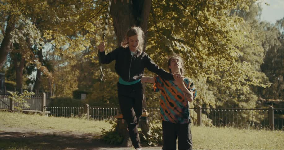 A man holds on to a woman as she tries to balance and steady herself on a tightwire