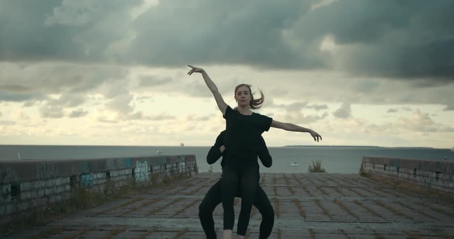 A man lifts a woman up in the air and sets her down as they dance on the shore
